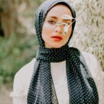 Stylish portrait of a woman outdoors in Cairo, showcasing modern fashion with a polka dot scarf.